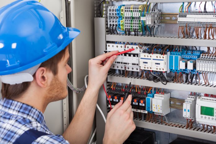 Technician Examining Fusebox With Multimeter Probe