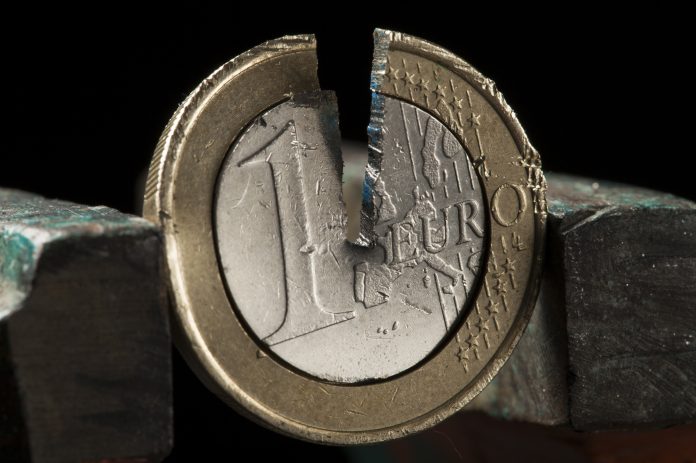 Photo illustration of damaged one Euro coin being held in a vise