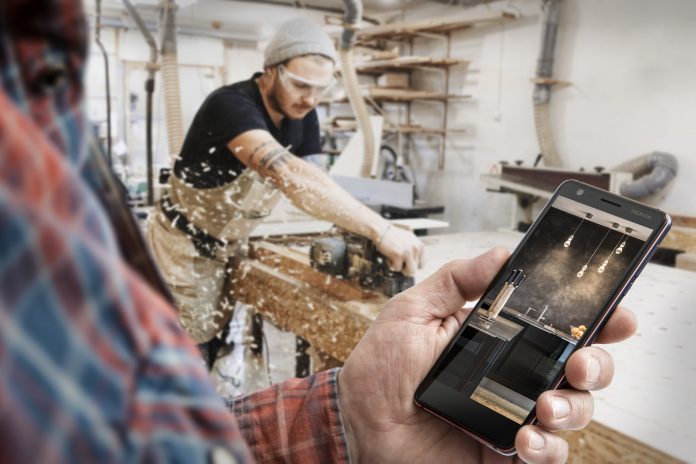 Carpenter working with electric planer on wooden plank in workshop. Craftsman makes own successful small business. Nokia 3.1