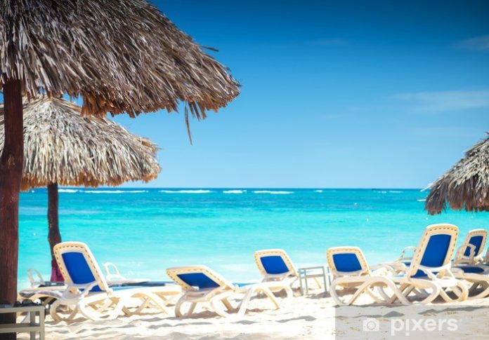 tropical view of a beach with umbrellas and beach chairs