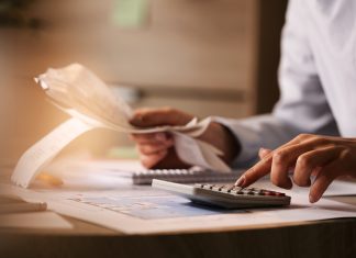 Close-up of business accountant using calculator while working i
