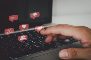 Hand pressing the keyboard of a laptop computer. Icon virtual interface technology concept. Social networks bully Gossips, quarrels, and fake news of a divided society.