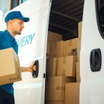 Courier Takes out Cardboard Box Package from Openned Delivery Van and Closes the Door. Delivering Postal Parcel to Customer.