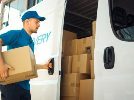 Courier Takes out Cardboard Box Package from Openned Delivery Van and Closes the Door. Delivering Postal Parcel to Customer.